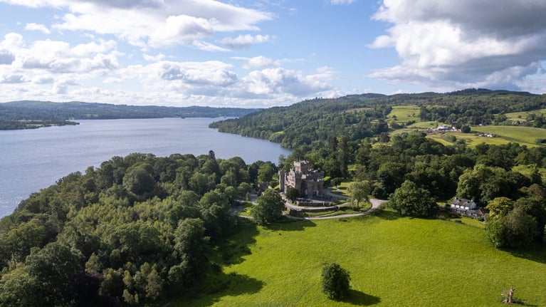 An aerial view of Wray Castle, with Wray Castle House on the right and Lake Windermere on the left, Cumbria